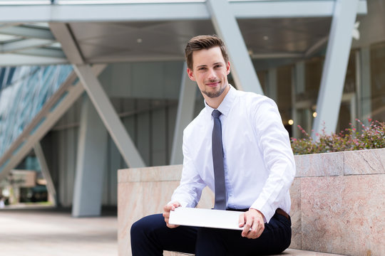 Caucasian businessman sitting at outdoor and hld with laptop com