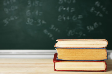 Stack of books on desk, on blackboard background