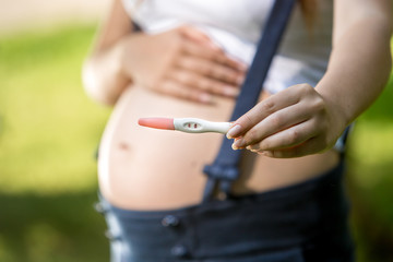 Closeup shot of pregnant woman holding positive pregnancy test