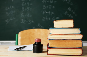 Stack of books on desk, on blackboard background
