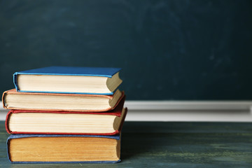 Stack of books on desk, on blackboard background