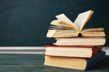 Stack of books on desk, on blackboard background
