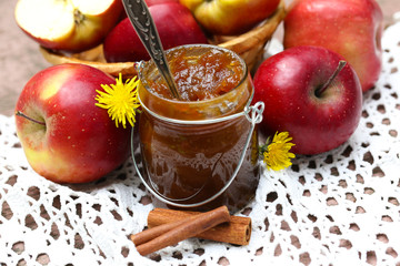 Apple jam in jar and fresh red apples outdoors
