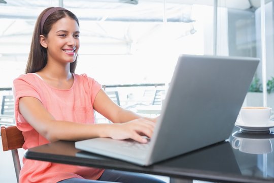 Young happy woman typing on the laptop