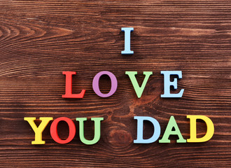 Inscription I LOVE YOU DAD made of colorful letters on wooden background