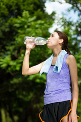 Young female athlete drinking water to refresh