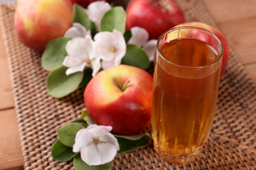 Glass of apple juice and apples on wooden table