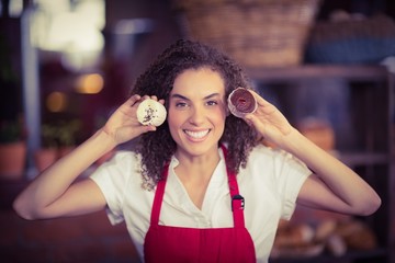 Smiling waitress showing two cupcakes