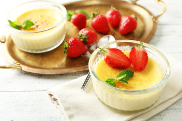 Creme brulee dessert with fresh strawberries and mint leaves, on color wooden background
