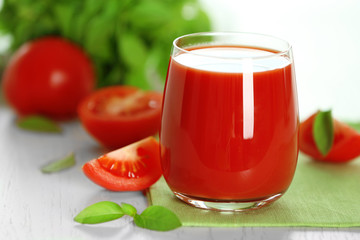 Tomato juice and fresh tomatoes on wooden table close-up