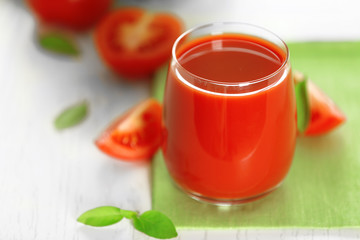 Tomato juice and fresh tomatoes on wooden table close-up