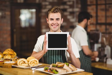 Smiling waiter holding a digital tablet