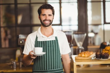 Smiling barista holding a cup of coffee