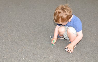 Fototapeta premium Portrait of a child writing with chalk on concrete