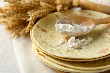 Stack of homemade whole wheat flour tortilla on plate, on light background