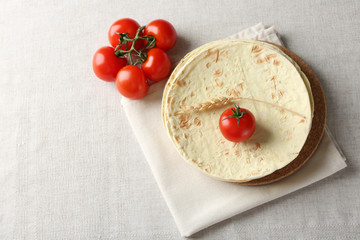 Stack of homemade whole wheat flour tortilla on napkin, on light background