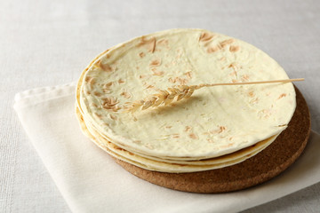 Stack of homemade whole wheat flour tortilla on napkin, on light background