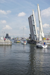 Fototapeta na wymiar White yachts pass through the gateway under a raised bridge