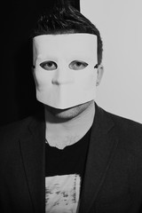 Man wearing a suit and white masquerade mask
