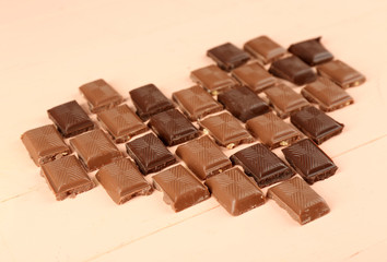 Chocolate pieces arranged in heart shape on light background