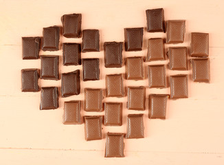 Chocolate pieces arranged in heart shape on light background