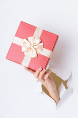Hand break through paper with red gift box