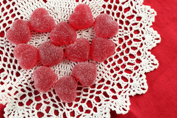 Gummy candies arranged in heart shape on fabric background