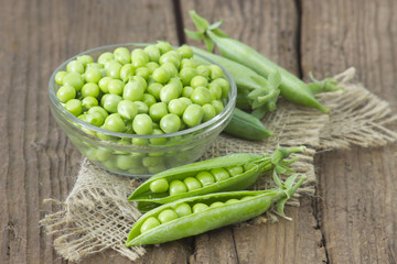 a bowl full of green peas on wooden background
