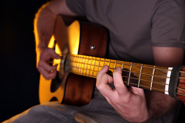 Obraz premium Young man playing on acoustic guitar close up