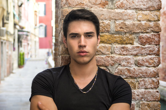 Attractive young man sitting against brick wall
