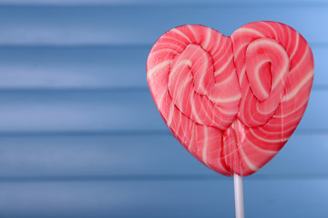 Bright lollipop in shape of heart on wooden background