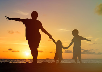 Fototapeta na wymiar father with kids silhouettes having fun at sunset