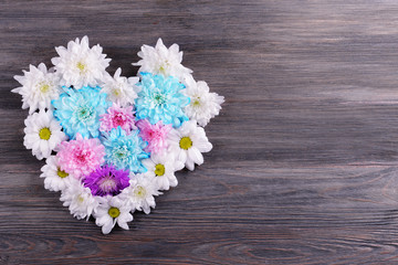 Beautiful flowers in heart shape on wooden background