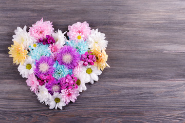 Beautiful flowers in heart shape on wooden background