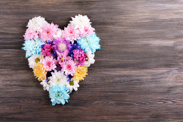 Beautiful flowers in heart shape on wooden background