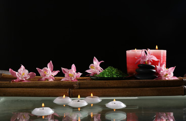 Beautiful spa composition with flowers and candles on black background