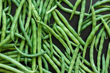 Whole French green string beans  on black rustic surface.