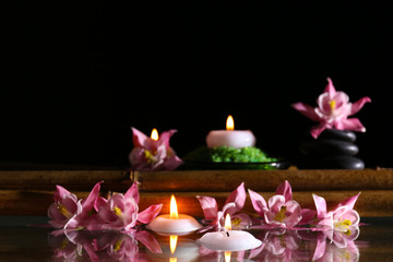 Beautiful spa composition with flowers and candles on black background