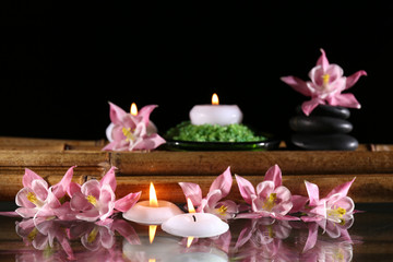 Fototapeta na wymiar Beautiful spa composition with flowers and candles on black background