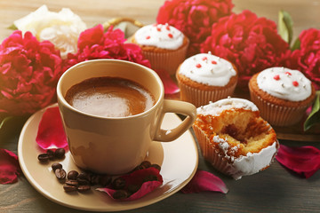 Composition with cup of coffee, muffins and peony flowers on wooden background