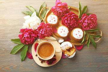 Composition with cup of coffee, muffins and peony flowers on wooden background