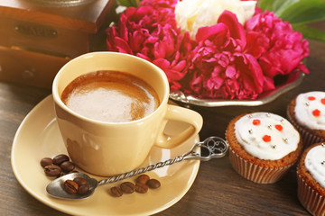Composition with cup of coffee, muffins and peony flowers on wooden background