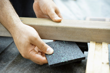 Schreiner oder Handwerker setzt Granulatpad unter Holzbalken für Terrasse