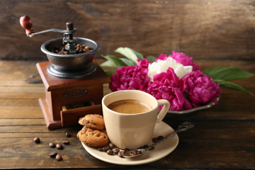 Composition with, coffee grinder, cup of coffee and peony flowers on wooden background