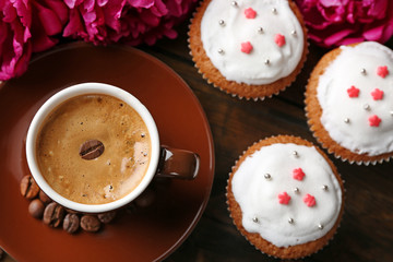 Composition with cup of coffee, muffins and peony flowers on wooden background