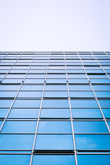 Business landscape. Low angle view of a glass and steel skyscraper giving the appearance of a...