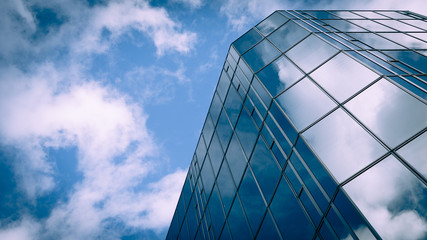 Business future. Low angle view of a glass and steel skyscraper blending into and reflecting the...