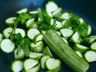 Cutting zucchini for cooking with mint in a frying pan