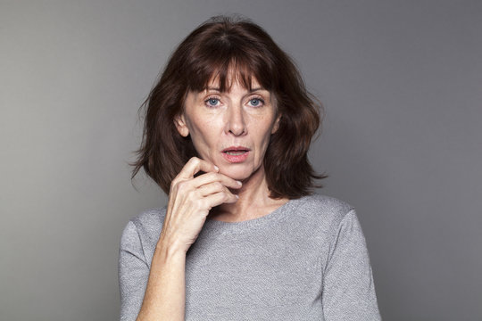 unhappy mature woman with brown hair and grey sweater thinking,looking concerned or questioning