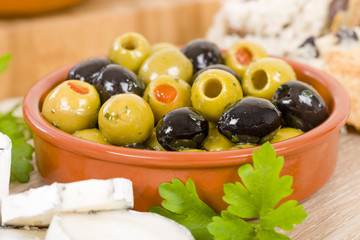 Olives - Bowl of a variety of black and green olives with herbs and olive oil.

